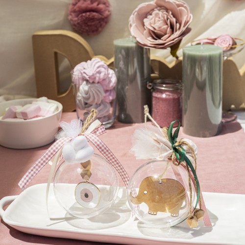 Μπομπονιέρες με διάφανο κουτί σε σχήμα μπάλας διακοσμημένες με ξύλινο στοιχείο ελεφαντάκι, μεταλλικό στοιχείο μάτι και διάφορες κορδέλες