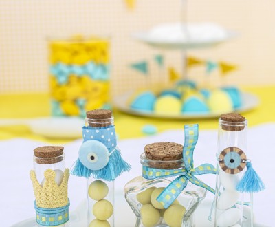 Μπομπονιέρες με διάφανα μπουκαλάκια σε διάφορα μεγέθη και σχήματα διακοσμημένες με κεραμικό και ξύλινο στοιχείο ματάκι, διάφορες κορδέλες και τρέσες