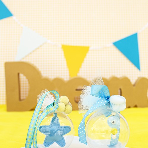 Μπομπονιέρες με διάφανο κουτί σε σχήμα μπάλας διακοσμημένες με υφασμάτινο αστέρι, κεραμικό στοιχείο μάτι και διάφορες κορδέλες