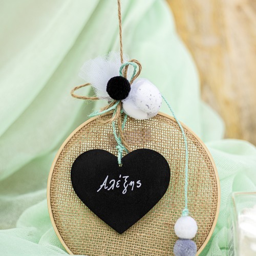 Μπομπονιέρα με ξύλινο στεφάνι και ύφασμα τσουβαλέ διακοσμημένη με ξύλινο στοιχείο πίνακα σε σχήμα καρδιάς και διάφορες μπάλες πομ πομ