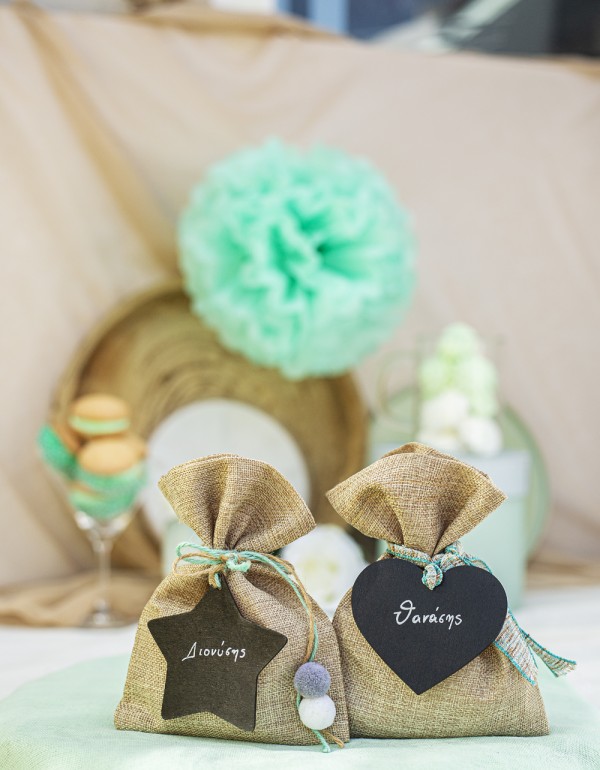 Μπομπονιέρες με πουγκί τσουβαλέ διακοσμημένες με ξύλινα στοιχεία πίνακα σε σχήμα καρδιάς και αστέρι, μπάλες πομ πομ και διάφορα κορδόνια