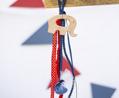 Κρεμαστή μπομπονιέρα με ξύλινο στοιχείο ελεφαντάκι διακοσμημένη με ρεγιόν κορδόνι, τρέσα με πον πον και διάφορες κορδέλες