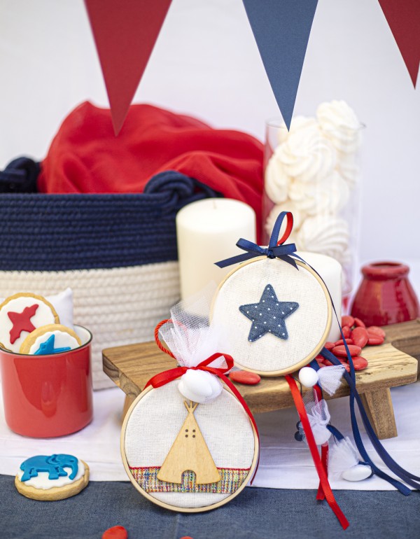 Μπομπονιέρες με ξύλινο στεφάνι και λευκό πουγκί διακοσμημένες με ξύλινο στοιχείο tipi τέντα, υφασμάτινο πουά αστέρι και διάφορες κορδέλες