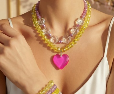 Κολιέ και βραχιόλια με λαμπερά κρύσταλλα σε παστέλ αποχρώσεις, που χαρίζουν φωτεινότητα και κομψότητα, συνδιασμένα με ασημί αιματίτη και φούξια διάφανο μοτίφ που δημιουργεί ένα μοντέρνο, καλοκαιρινό αποτέλεσμα με διακριτική λάμψη