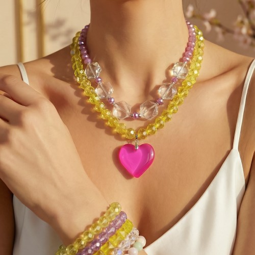 Κολιέ και βραχιόλια με λαμπερά κρύσταλλα σε παστέλ αποχρώσεις, που χαρίζουν φωτεινότητα και κομψότητα, συνδιασμένα με ασημί αιματίτη και φούξια διάφανο μοτίφ που δημιουργεί ένα μοντέρνο, καλοκαιρινό αποτέλεσμα με διακριτική λάμψη