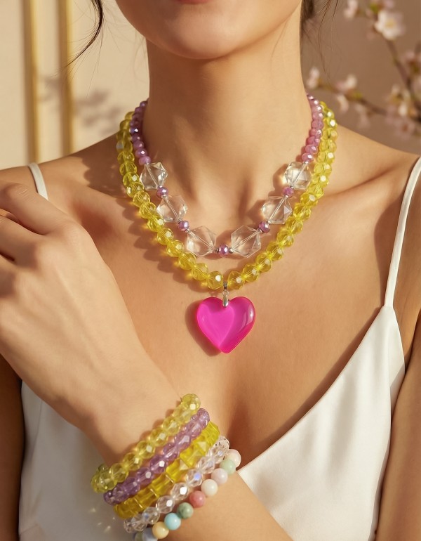 Κολιέ και βραχιόλια με λαμπερά κρύσταλλα σε παστέλ αποχρώσεις, που χαρίζουν φωτεινότητα και κομψότητα, συνδιασμένα με ασημί αιματίτη και φούξια διάφανο μοτίφ που δημιουργεί ένα μοντέρνο, καλοκαιρινό αποτέλεσμα με διακριτική λάμψη